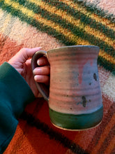 Load image into Gallery viewer, Large geen and pink handmade mug against plaid wool blanket. 
